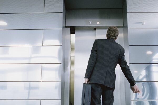 Businessman in front of elevator holding briefcase